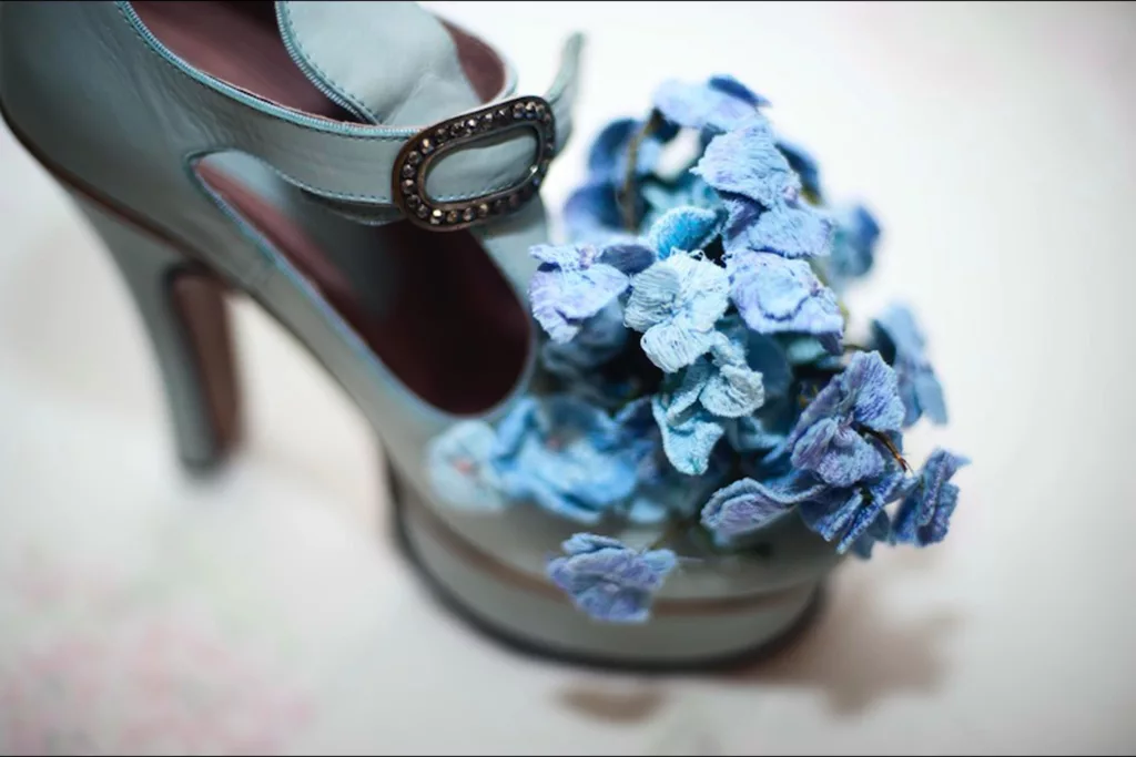 Close up of the platform blue leather court shoe called hydrangea. True to its name it has an impressive cluster of handcrafted, embroidered hydrangeas at toe and filling the T- bar area. The flowers are many hues of blue and lilacs.