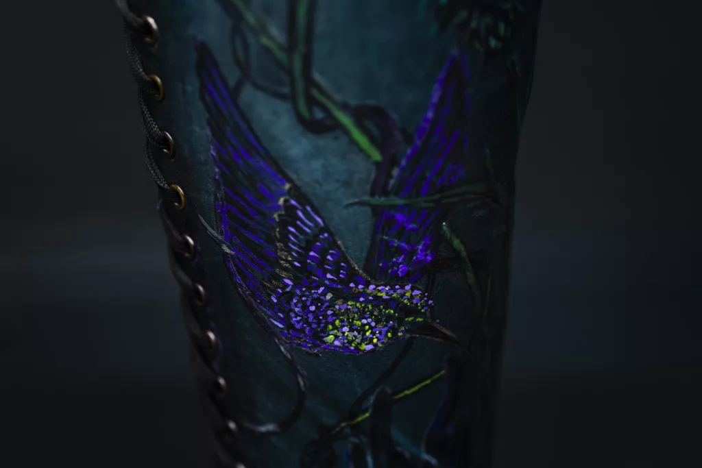 Purple and green bird decoration on a dark blue lace-up boot.