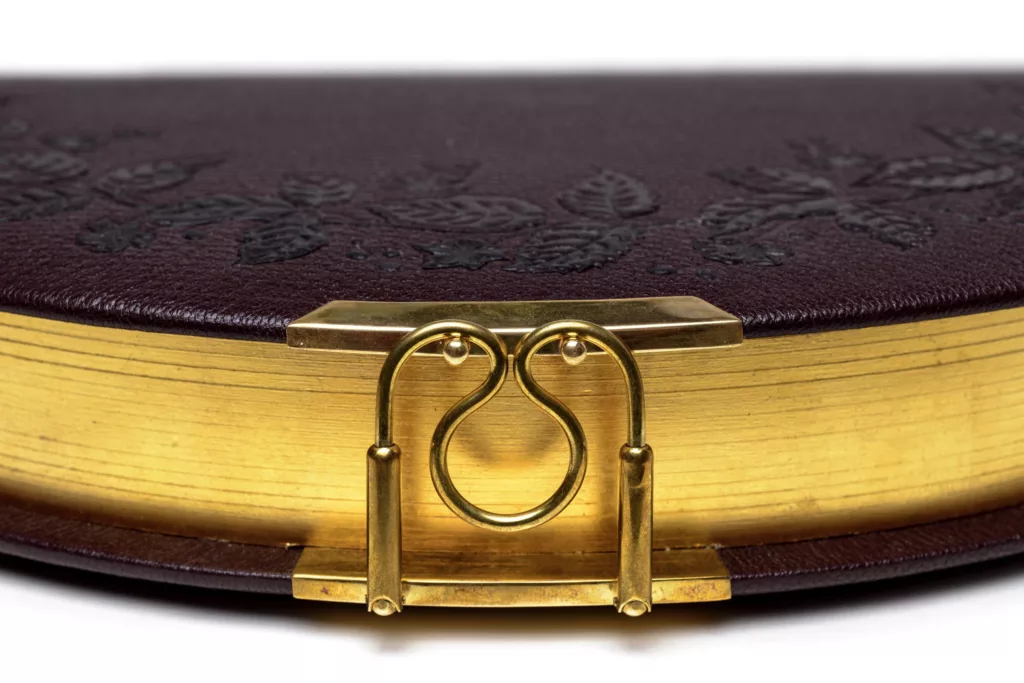 The Conduit Clutch is inspired by Victorian adornment and artifacts. With a crest of berries and foliage onlayed and embossed. Hollowed cavity for holding personal items within, this photo shows a close up of the clasp, handcrafted and sprung in brass.