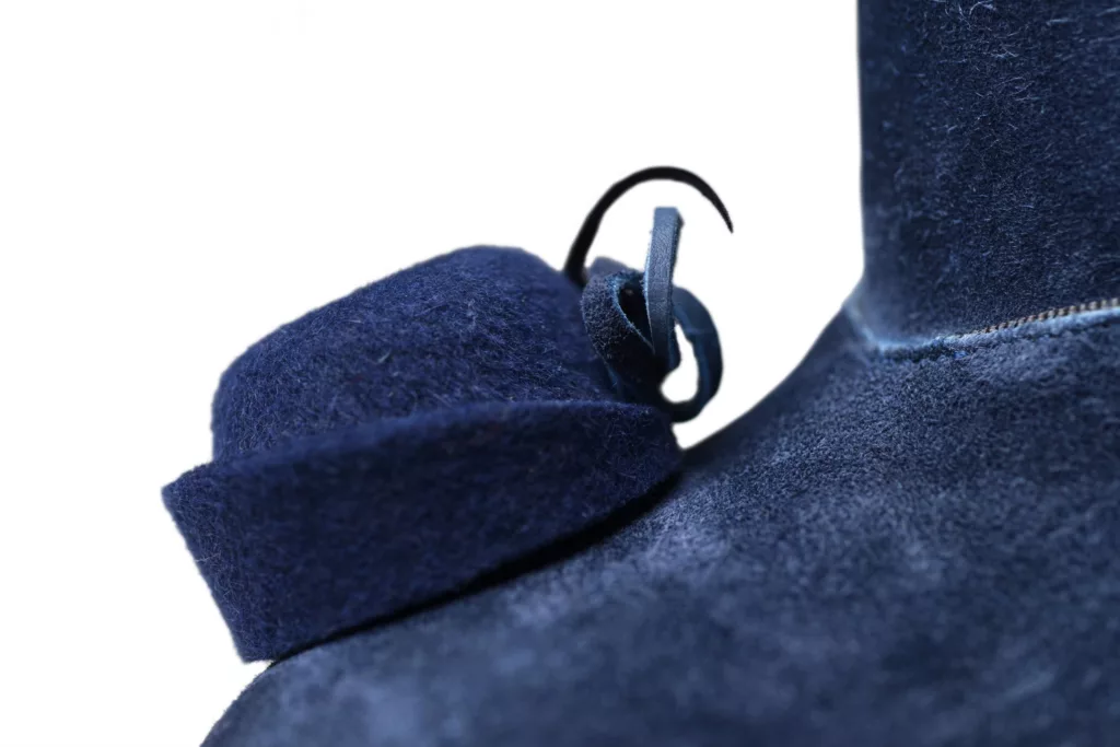 Close up of the toe of a blue suede, high vamp platform shoe. This character full pair have stand up collars, each toe has a miniature felt hat specially created by a milliner. Oak bark leather tanned soles and top pieces.