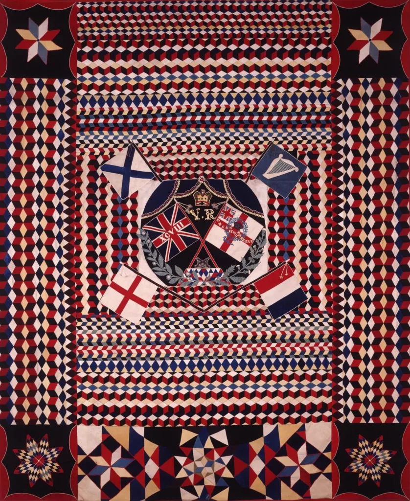 Red, white and blue patchwork textile with geometric patterns and flags.