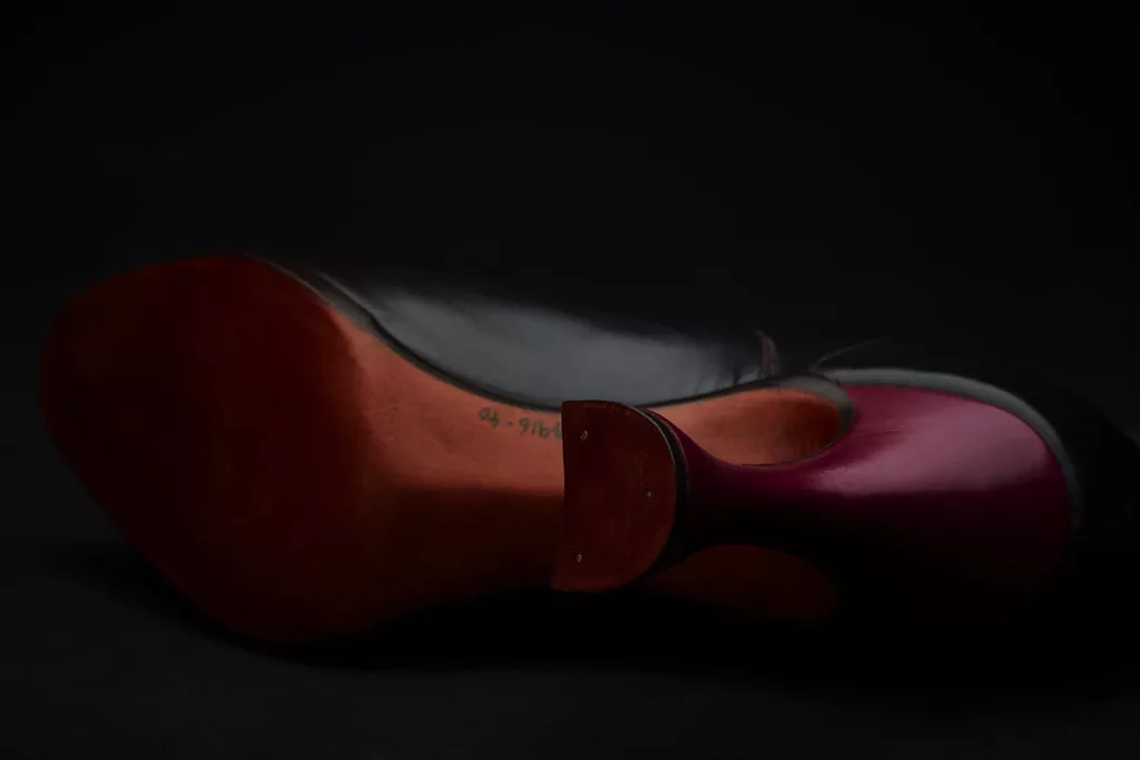 This photo shoes the underside of the ‘Carnal Flower’ Bootie by Caroline Groves. The underside of the heel reveals a beautiful shaped top piece in Baker’s Oak bark tanned leather, with three tiny nails. This heel is a flare shape with wonderful curves. The leather sole has been carefully and expertly moulded. A magenta leather is carefully covering the heel and the rest of the boot is in a fine black calf skin leather