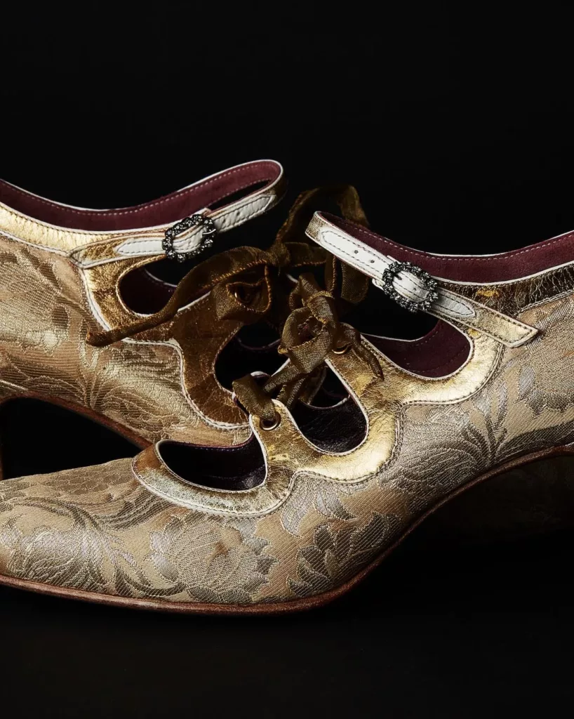A pair of elegant, heeled shoes handcrafted in Indian gold silk brocade, featuring an ankle strap with Swarovski crystal buckles and ghillie lace panels with 22t gold applied. Louis heels with leather stacks. Lining is a rich burgundy kid.