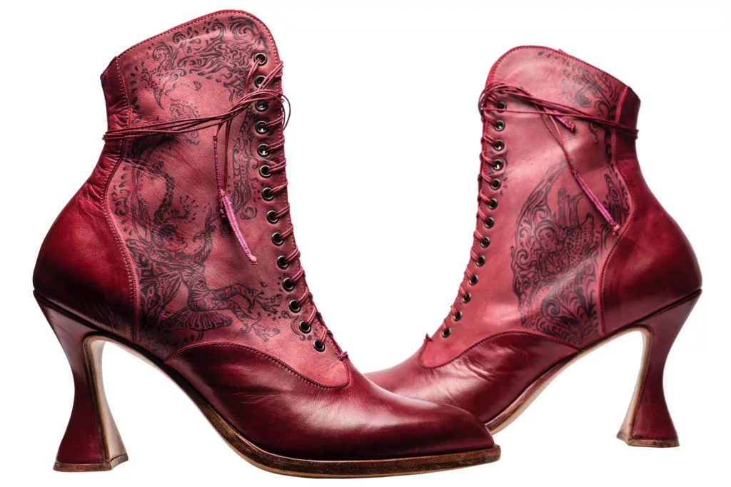 Hand inked art works on a luxurious ankle length lace up boot. Detailed , romantic lines make up fairy like figures and floral designs against a red leather