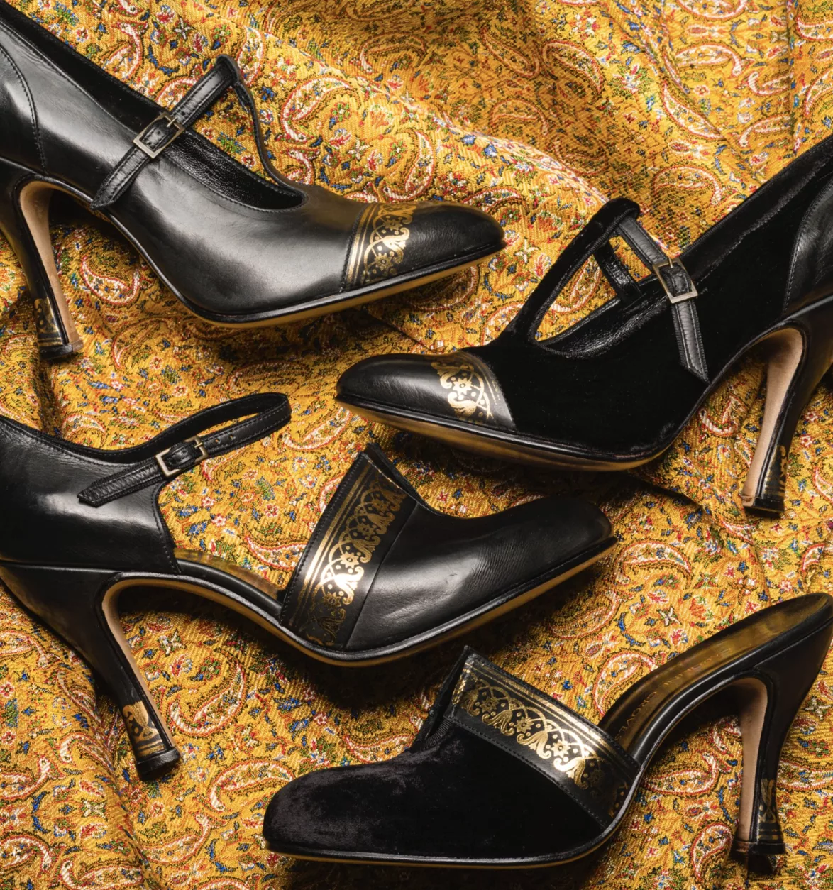 Screenshot 2026-10-28 at 09.54.00 Pair of black ankle boots with sculptural gold-tone heel details.